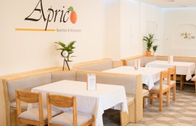 Gastraum mit Tischen und Stühlen sowie weißer Tischwäsche