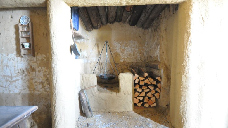 Interior view of a rustic room with fireplace and pile of wood.