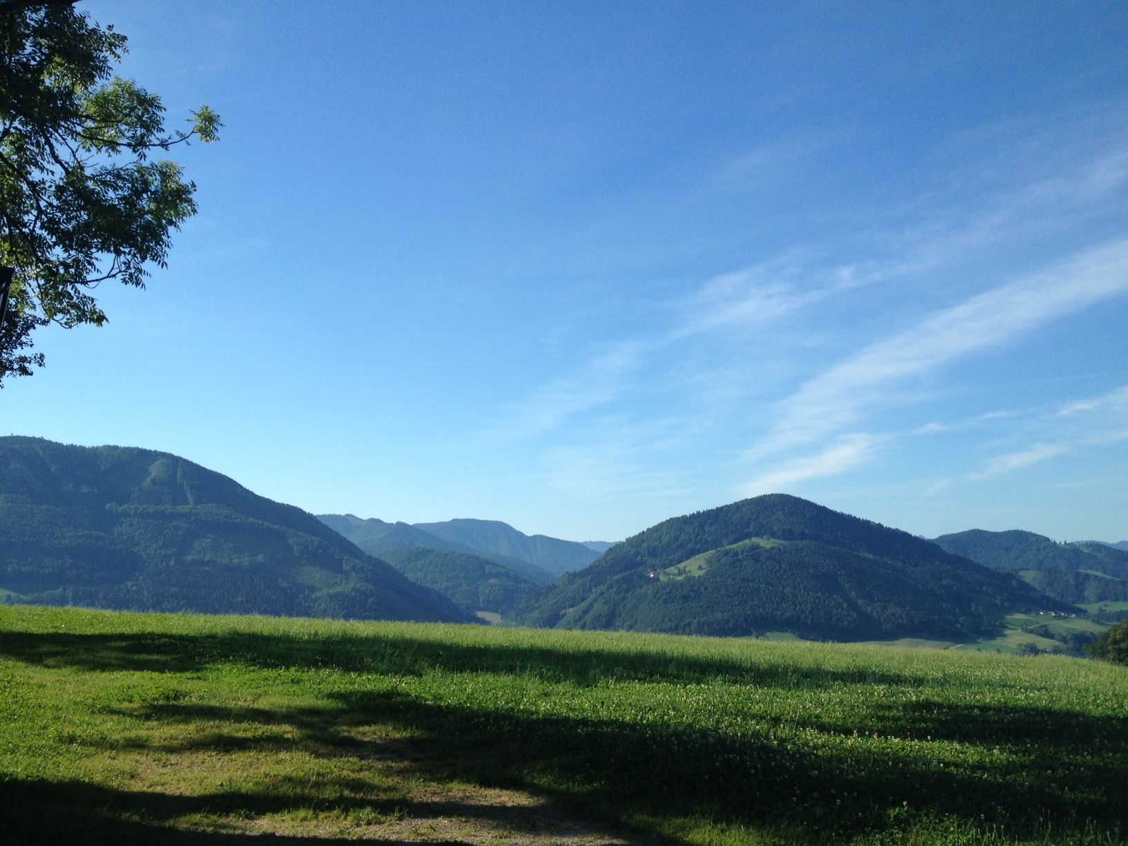 Landschaft mit grünen Hügeln und blauem Himmel.