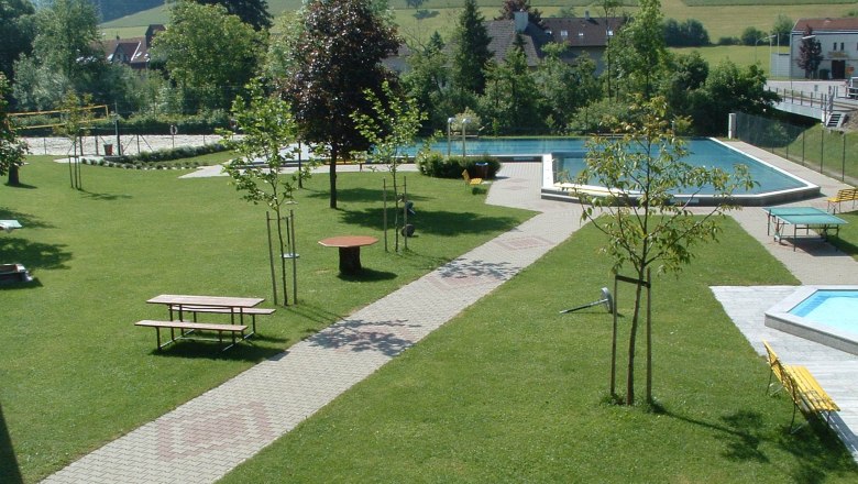 Green park with swimming pool and benches.