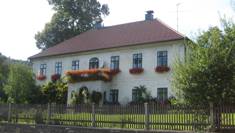 Ein zweistöckiges Haus mit roten Dachziegeln und Blumenkästen an den Fenstern.
