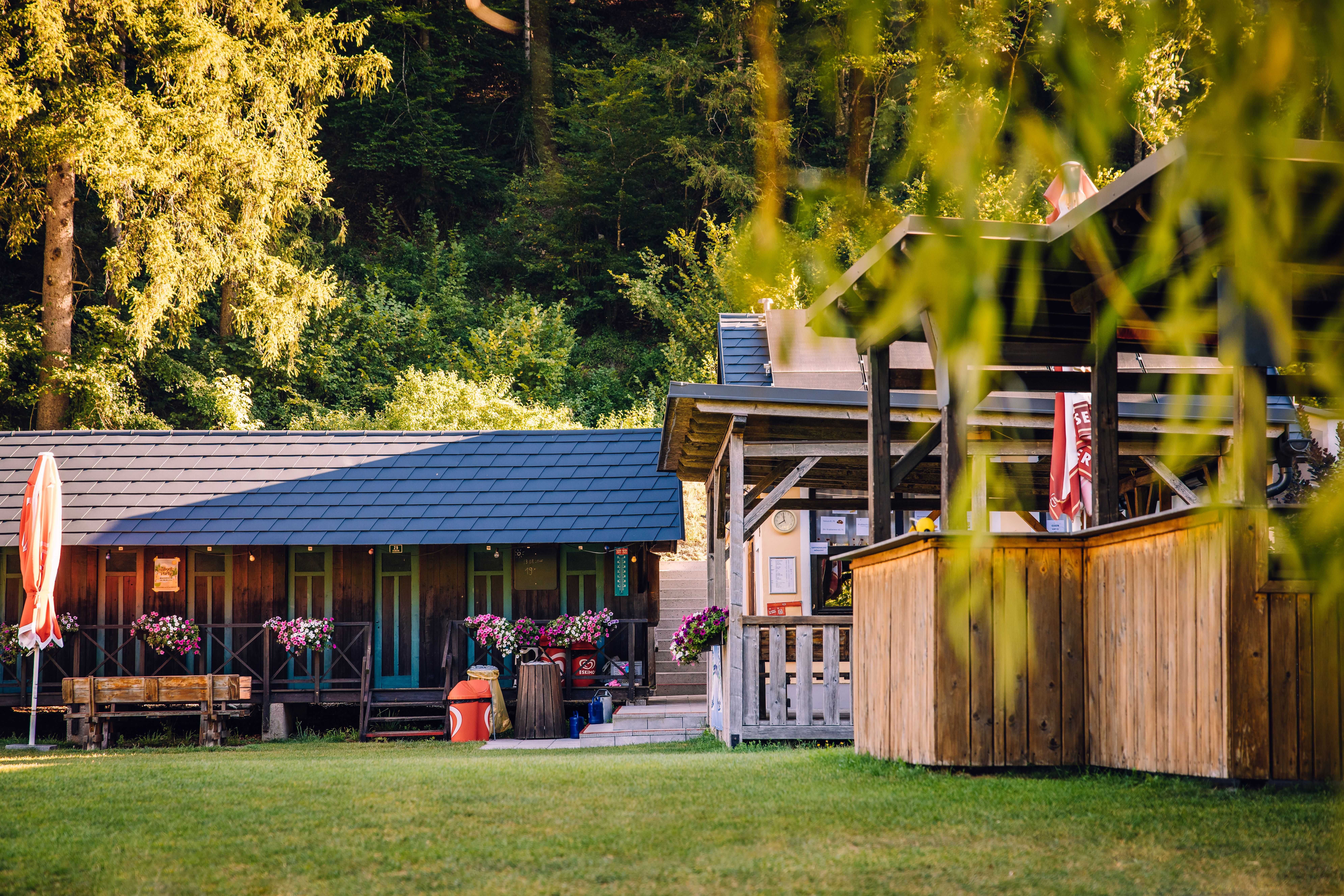 Holzgebäude mit Blumenschmuck und überdachter Terrasse in einer grünen Anlage in Hollenstein an der Ybbs.