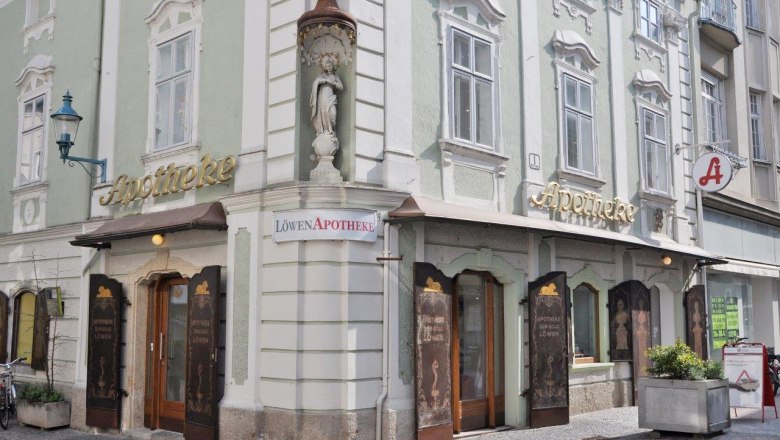 Historic pharmacy with a green façade and golden lettering in a town.