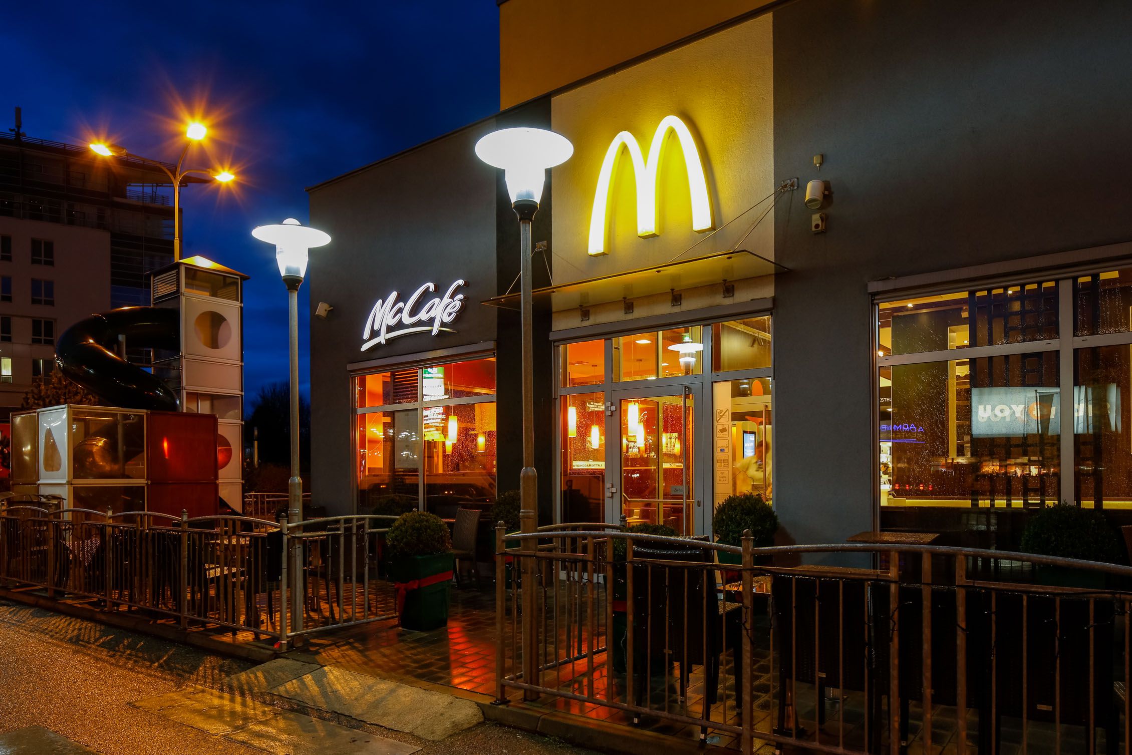 Außenansicht eines McDonald's Restaurants bei Nacht mit beleuchtetem Logo und McCafé-Schild.