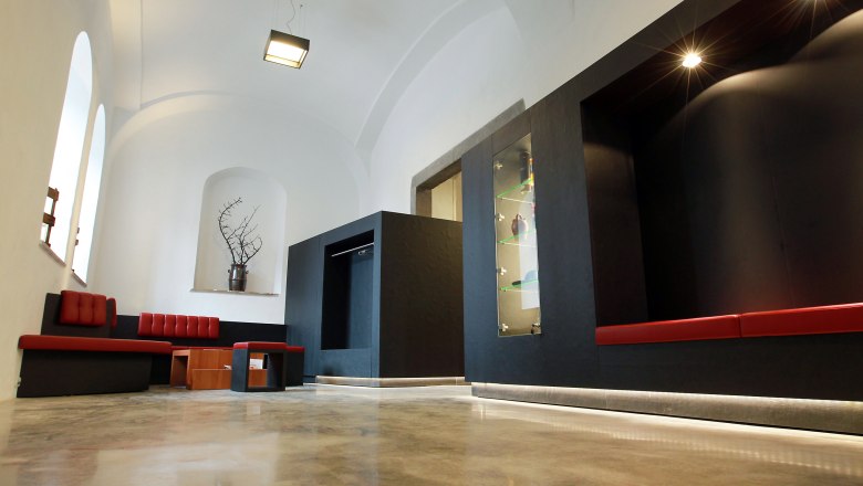 Moderner Innenraum mit roten Sitzbänken und schwarzen Wänden.