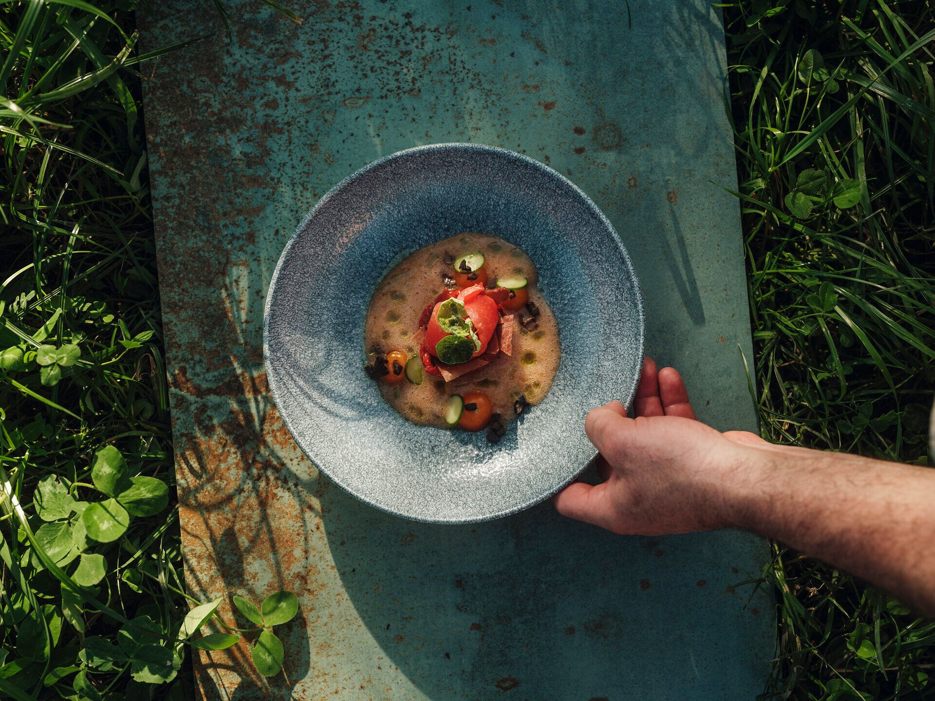 Ein kunstvoll angerichteter Teller mit frischen, regionalen Zutaten lädt zum Genießen ein. Die Farben und Texturen der Speisen harmonieren perfekt mit der natürlichen Umgebung, während die sanfte Brise die Aromen verstärkt. Hier wird Kulinarik zu einem Erlebnis für alle Sinne.