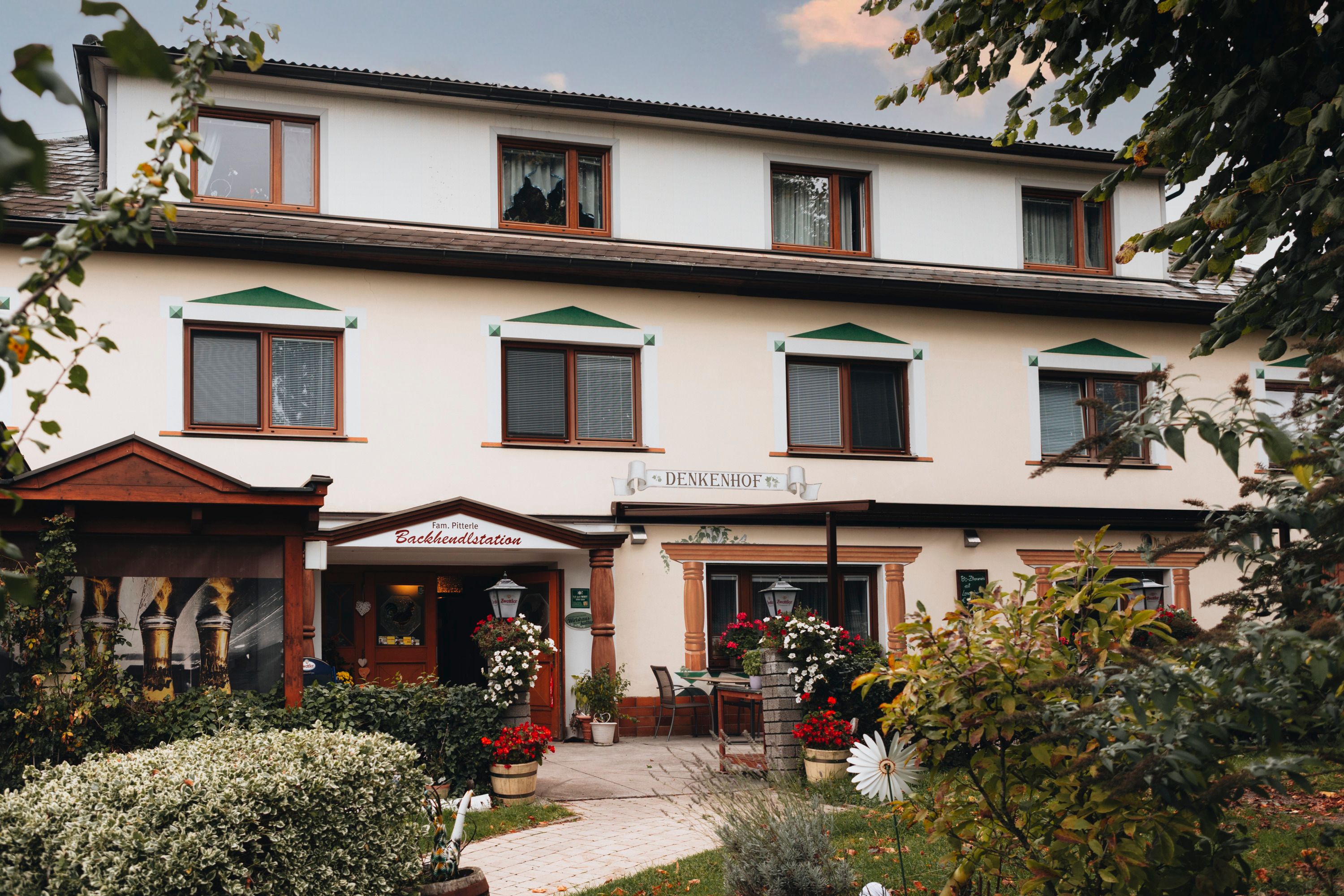 Ein traditioneller Gasthof mit Blumen und Bäumen im Vordergrund.