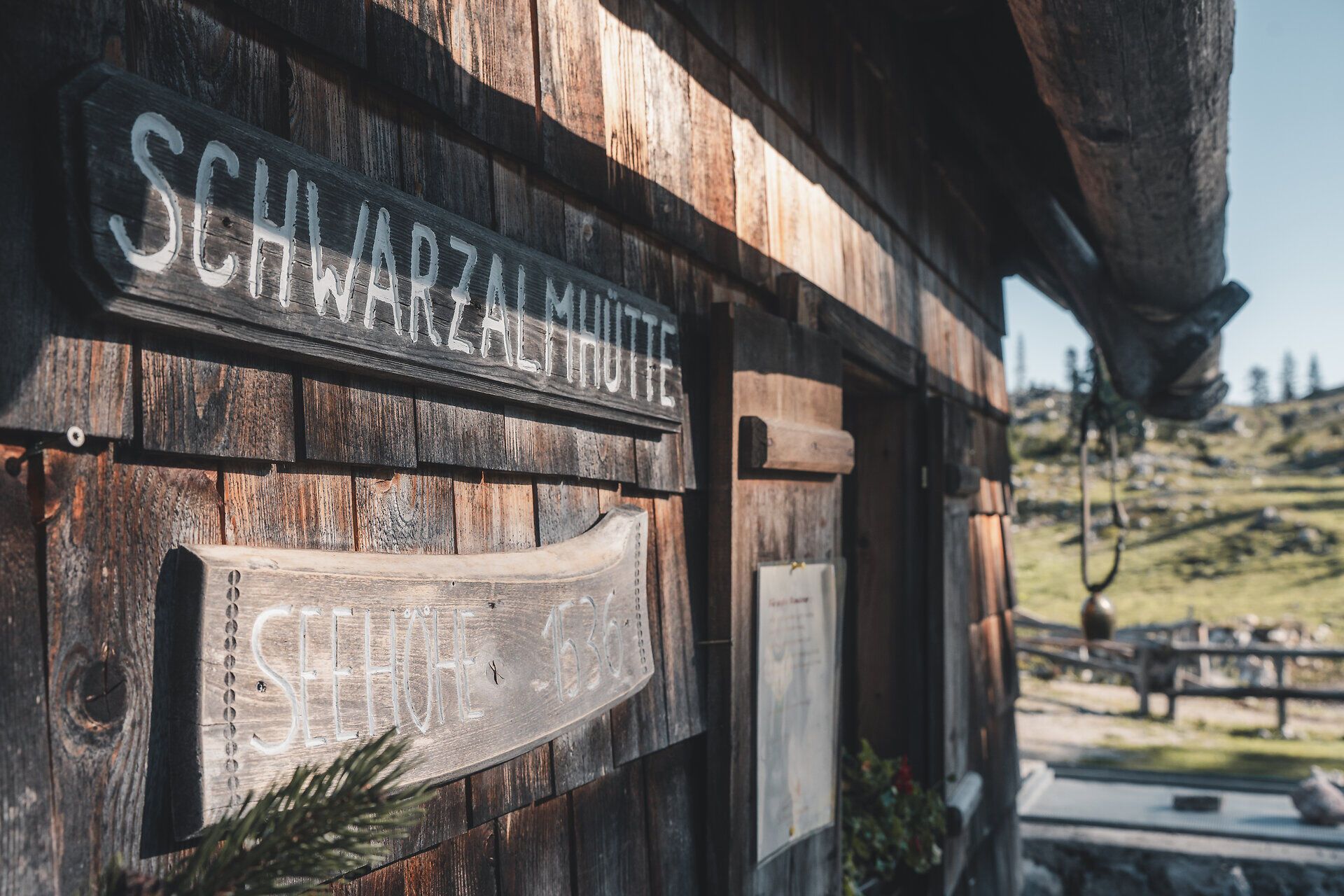 Holzschild „Schwarzalmhütte“ an der Außenfassade.