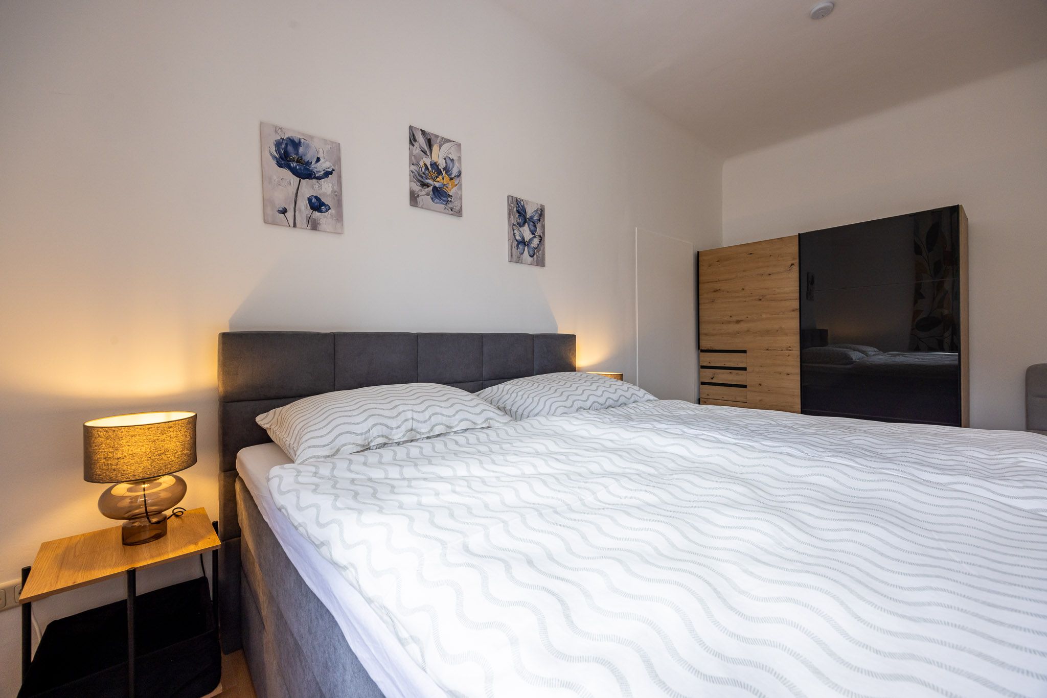 Schlafzimmer großem Bett, Nachttisch und einem Schrank.