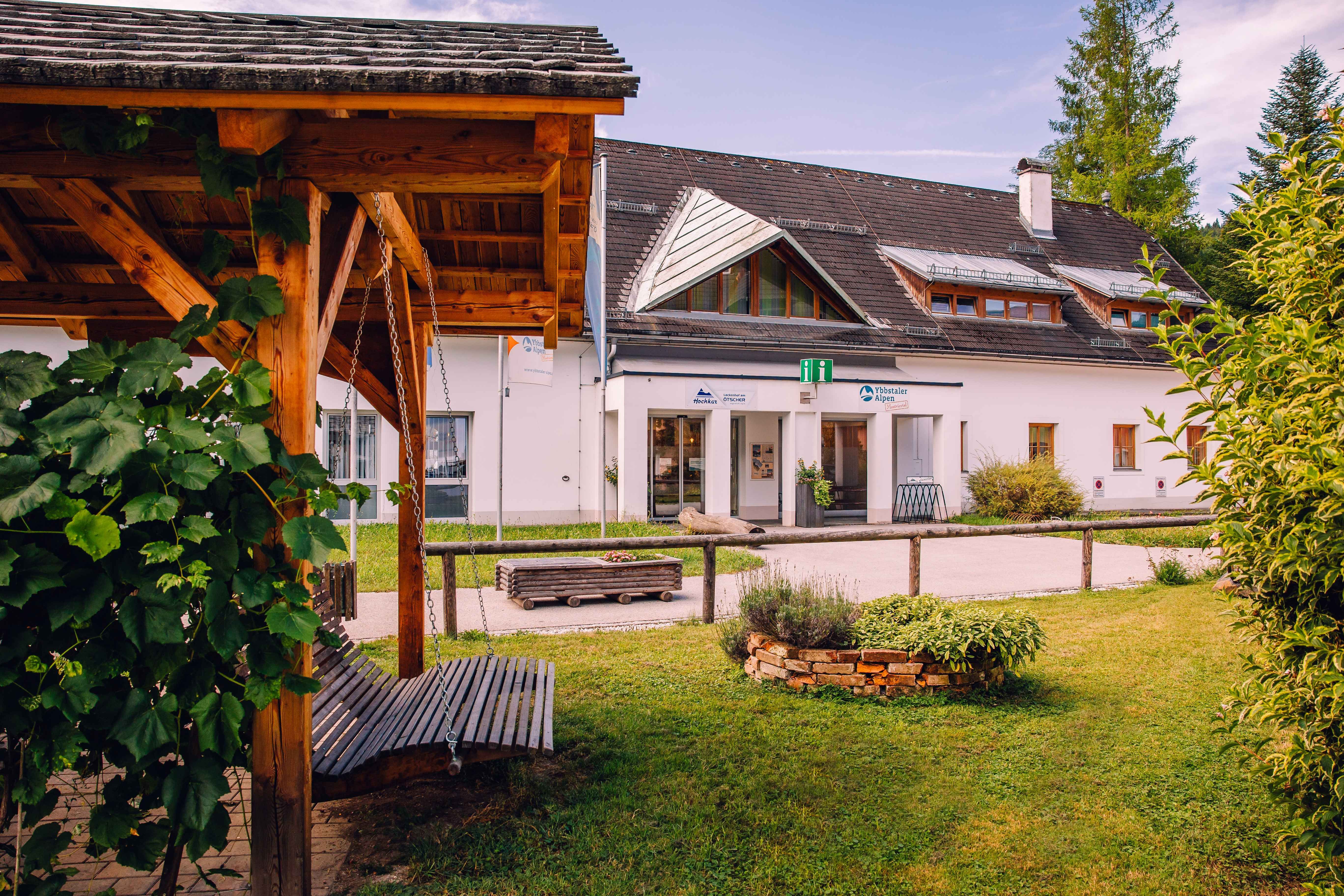 Holzpavillon im Garten vor einem Gebäude in Göstling mit Schild „Ybbstaler Alpen“ und begrüntem Innenhof.