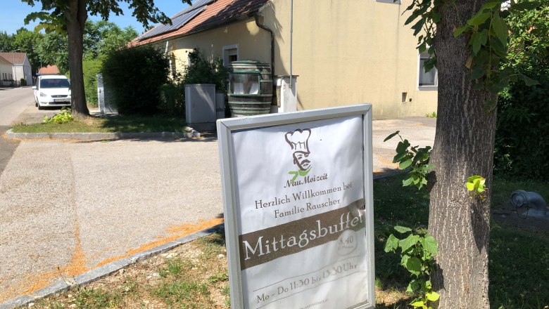 A sign in front of a building with the words 'Mittagsbuffet' and 'Herzlich Willkommen bei Familie Rauscher'.