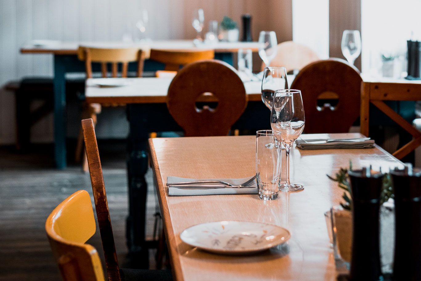 Ein gedeckter Tisch in einem gemütlichen Restaurant mit Holzmöbeln und Weingläsern.