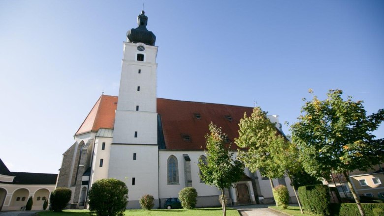 Wallfahrtskirche Mank mit Turm und rotem Dach, umgeben von Bäumen und Rasenfläche.