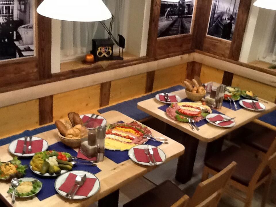 Ein gedeckter Tisch in einem rustikalen Restaurant mit Brot, Aufschnitt und Salaten.