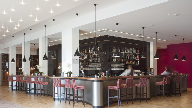 Moderne Hotelbar mit roten St&uuml;hlen und schwarzen H&auml;ngelampen.
