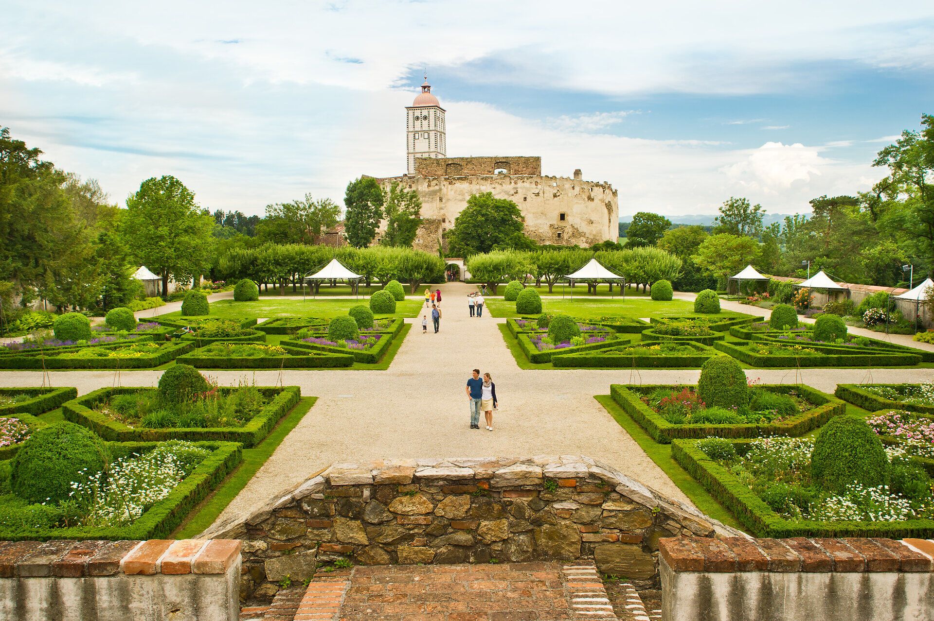 Die prachtvollen Gärten umgeben das majestätische Schloss und laden zu einem entspannenden Spaziergang ein. Hier, wo die Natur in voller Blüte steht, können Besucher die Ruhe und Schönheit der Umgebung genießen. Die harmonische Verbindung von Architektur und Landschaft schafft eine Atmosphäre der Erholung und Inspiration.