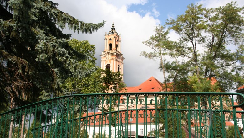 Stift Herzogenburg mit Turm und grünem Zaun im Vordergrund.