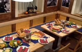 Ein gedeckter Tisch in einem rustikalen Restaurant mit Brot, Aufschnitt und Salaten.