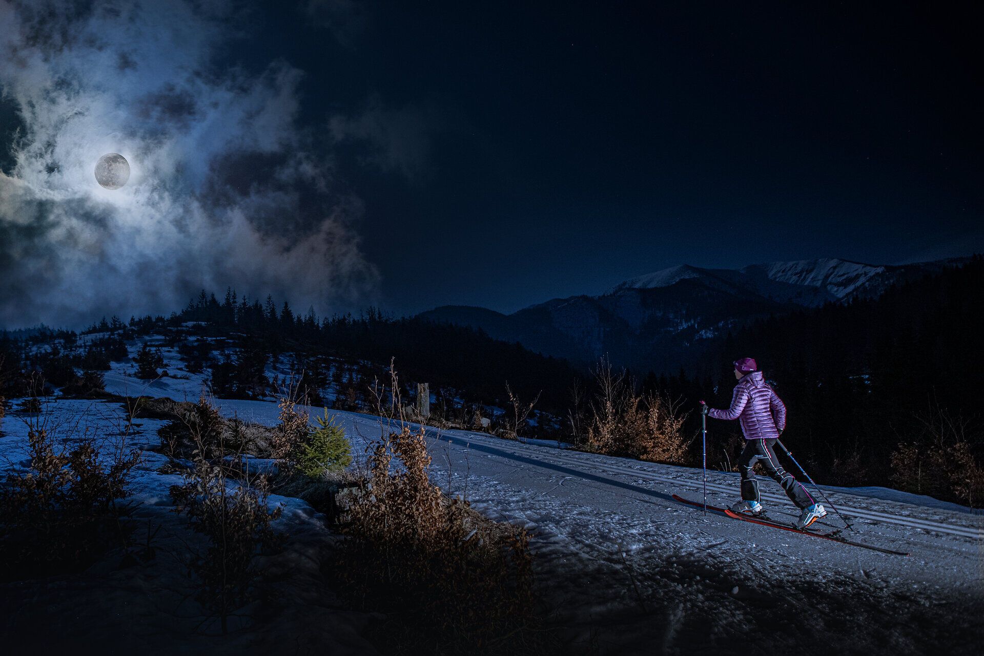 Unter dem strahlenden Mondlicht gleitet ein Skifahrer über die glitzernde Schneedecke, umgeben von der majestätischen Berglandschaft. Die ruhige Nachtluft ist erfüllt von der frischen Kälte des Winters, während die schneebedeckten Gipfel im Hintergrund geheimnisvoll leuchten. Ein unvergessliches Erlebnis für alle Wintersportbegeisterten, die die Stille der Nacht in den Bergen genießen möchten.