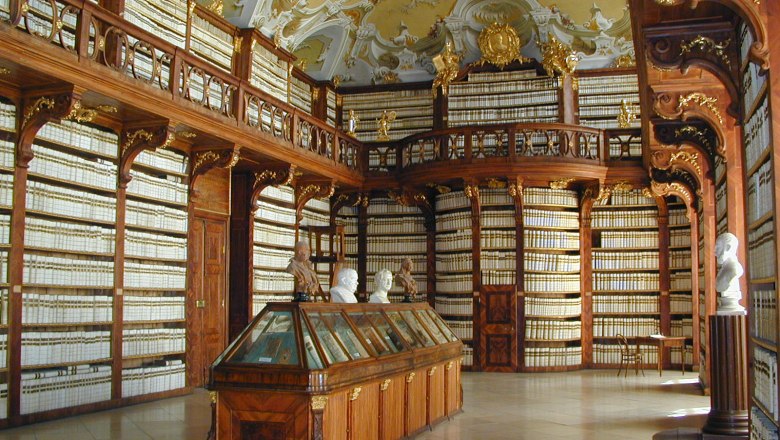 Innenansicht der Bibliothek im Stift Seitenstetten mit reich verzierten Holzregalen und Büsten.