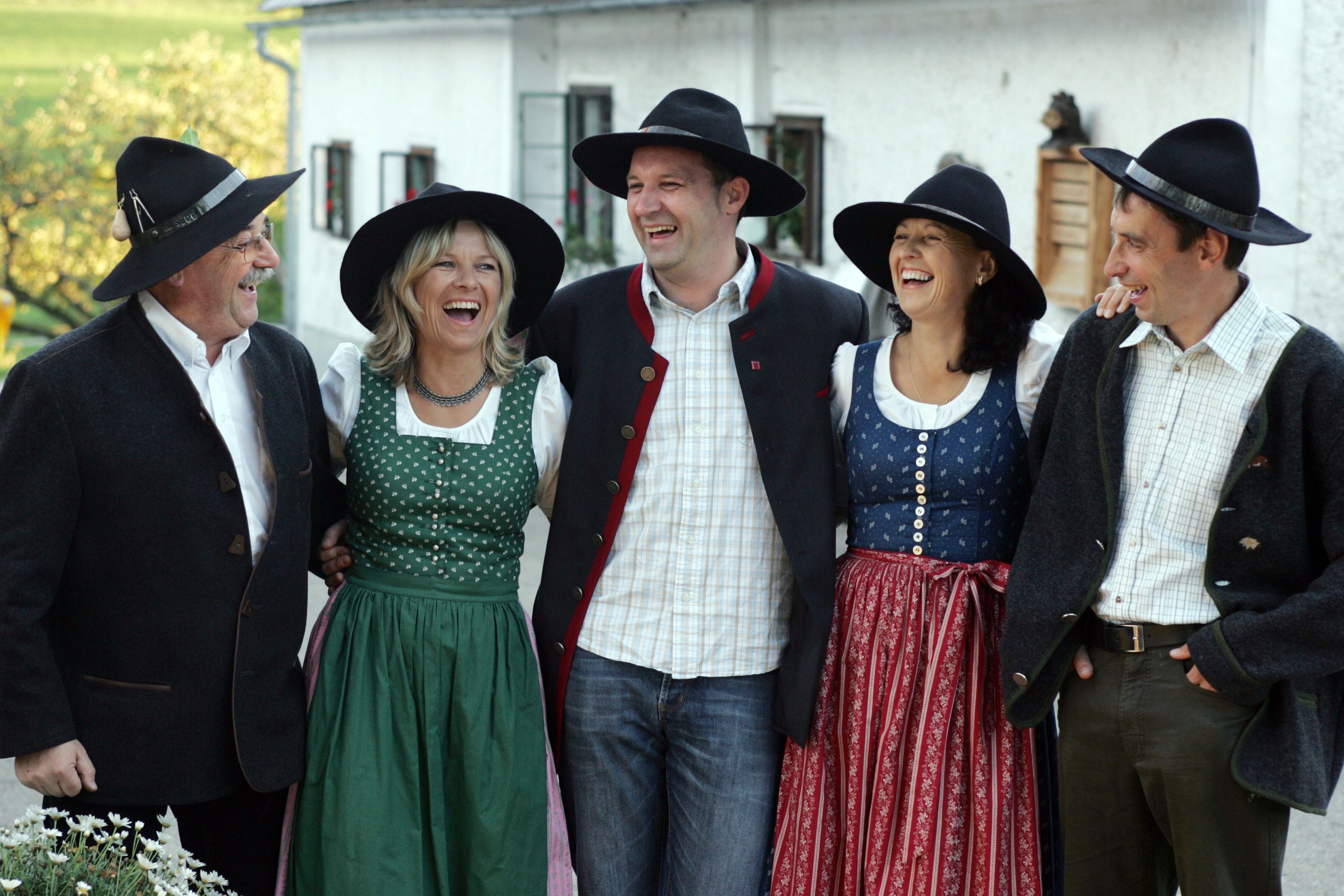 Gruppe von fünf Personen in traditioneller bayerischer Tracht, die fröhlich lachen.