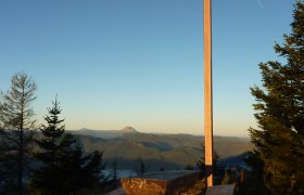 Summit cross on the Türnitzer Höger with wooden benches and mountain panorama in the background.