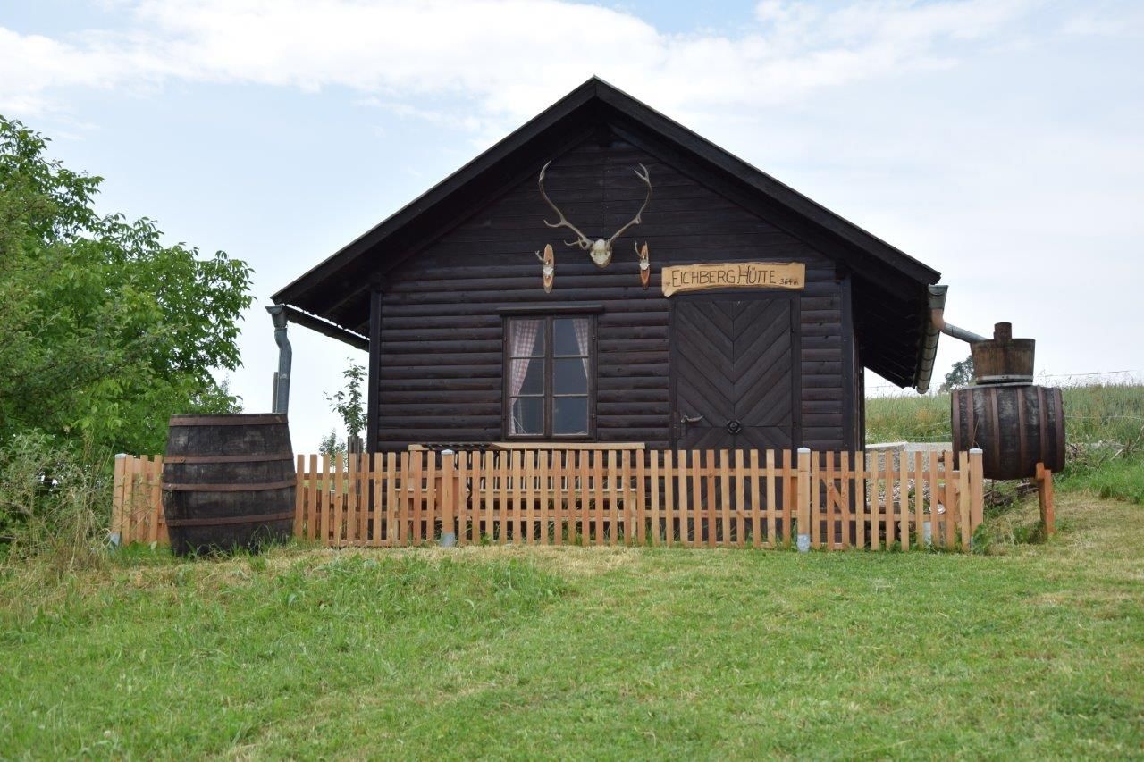 Eine rustikale Holzhütte mit einem Geweih über der Tür und einem Holzzaun davor.