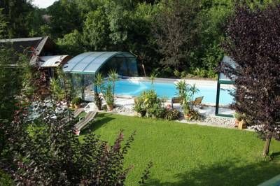 Ein Garten mit Pool und Überdachung, umgeben von Bäumen und Rasen.