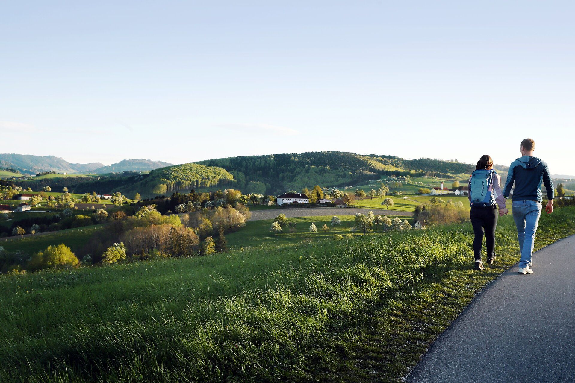 Paar spaziert auf Weg durch Frühlingslandschaft.