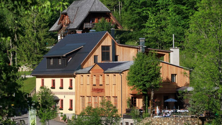 Ein traditionelles Gebäude mit Holzfassade in einer grünen Waldlandschaft.