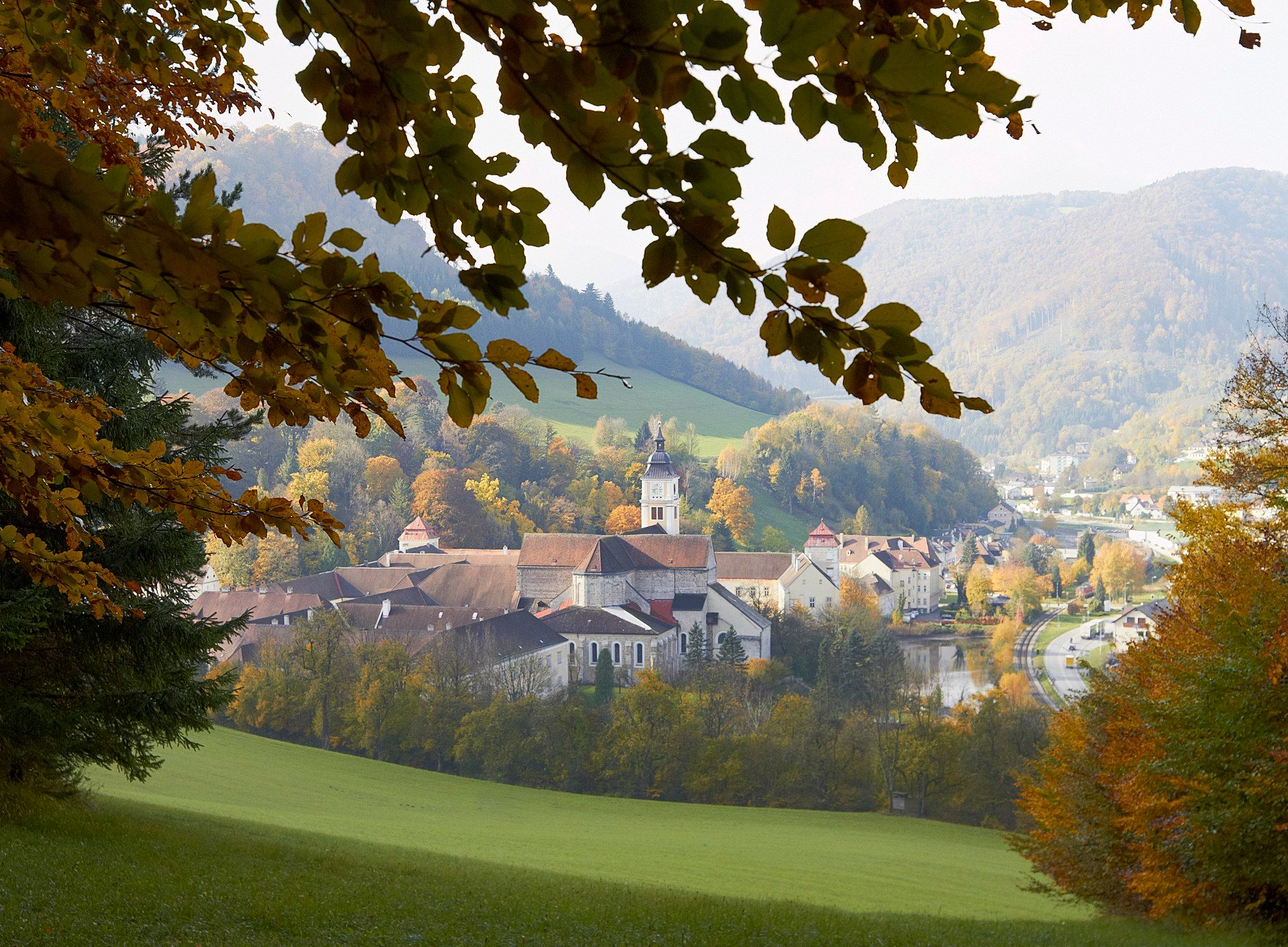 Stift Lilienfeld im Herbst mit buntem Laub und umliegenden Hügeln.
