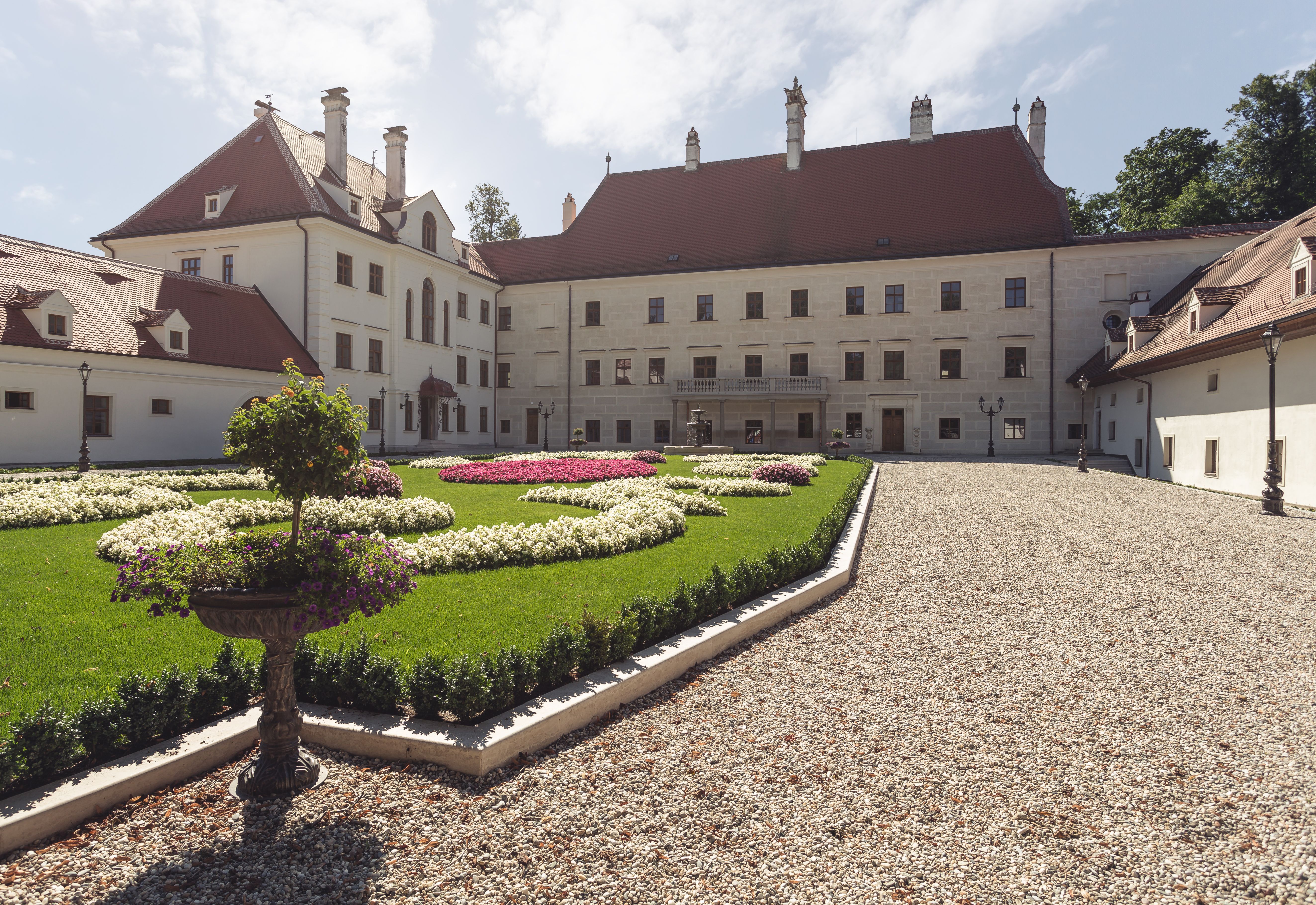 Schloss Thalheim mit gepflegtem Garten und Kiesweg.