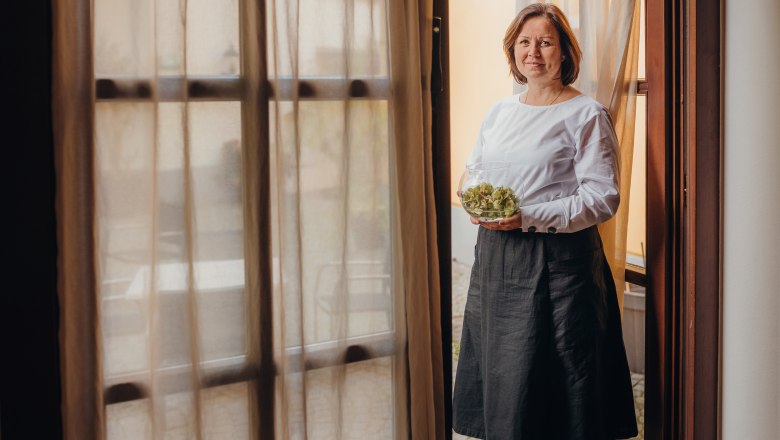 A woman stands in a doorway holding a bowl of salad.