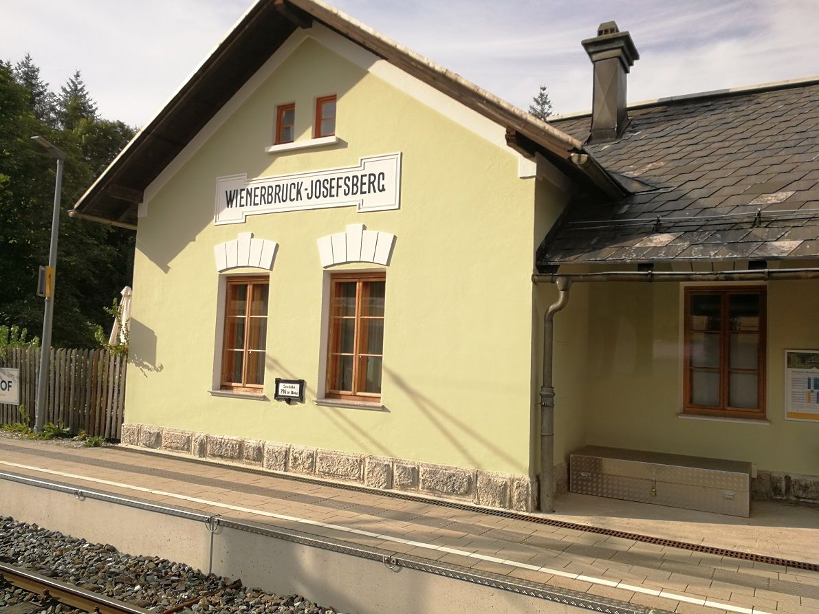 Bahnhofsgebäude Wienerbruck-Josefsberg mit gelber Fassade und Schieferdach.