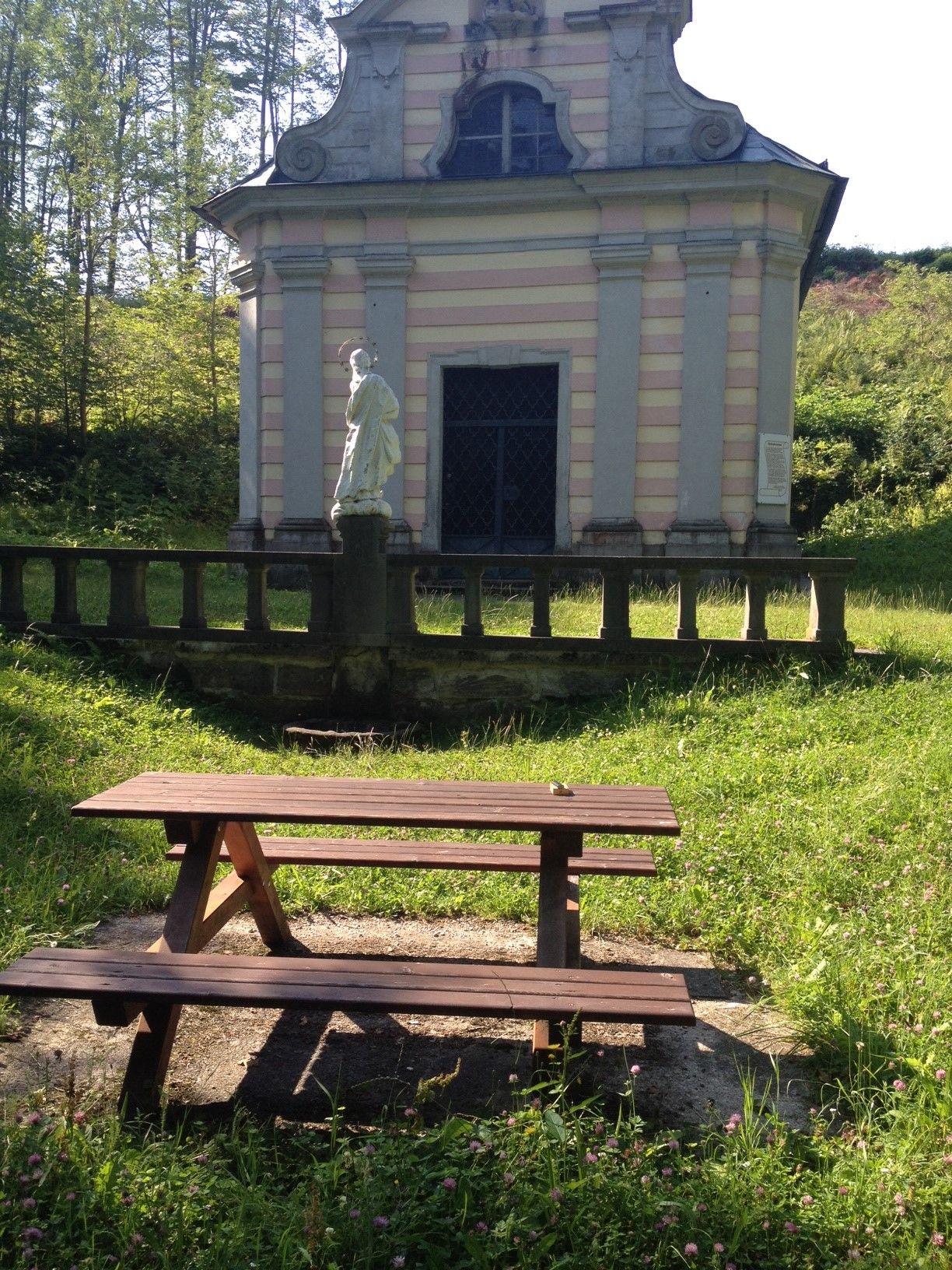 Picknicktisch vor einer kleinen Kapelle im Grünen.