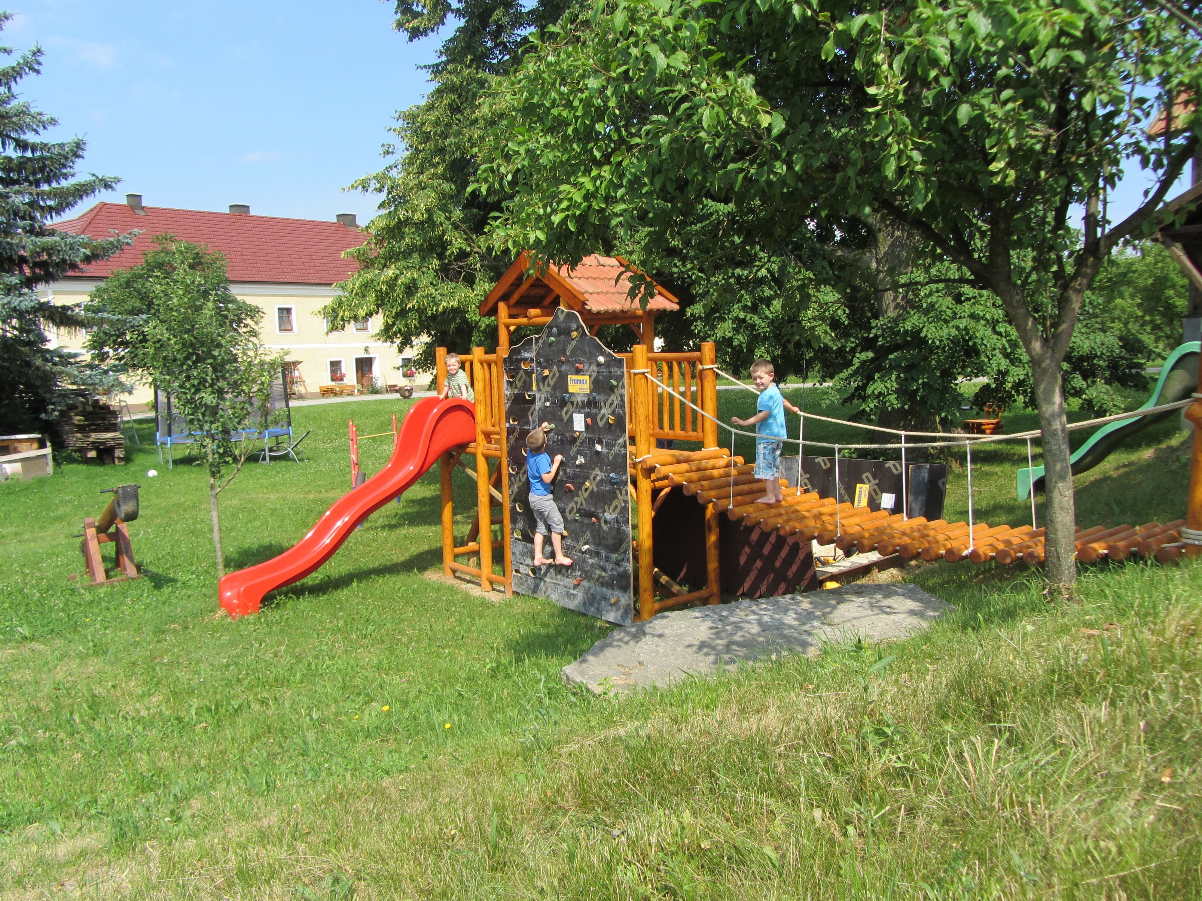 Spielplatz mit Klettergerüst, Rutsche und zwei Kindern beim Spielen.