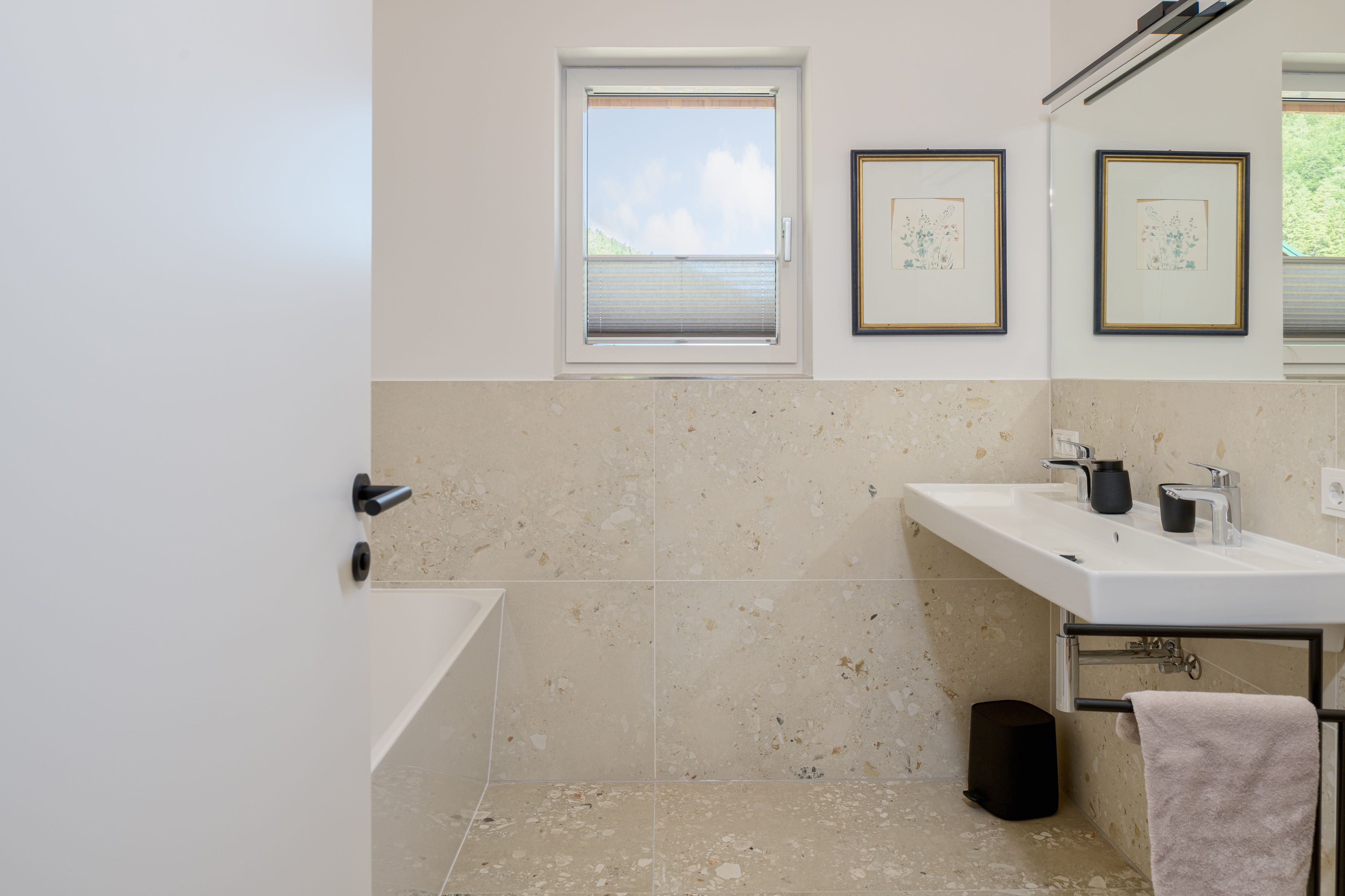 Modernes Badezimmer mit Fenster, Doppelwaschbecken und Badewanne.