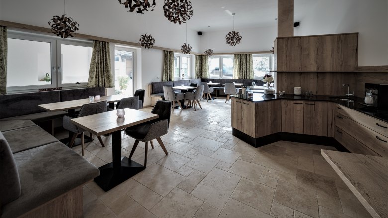 Moderner Frühstücksraum mit Holzmöbeln, grauen Polstern und dekorativen Lampen.