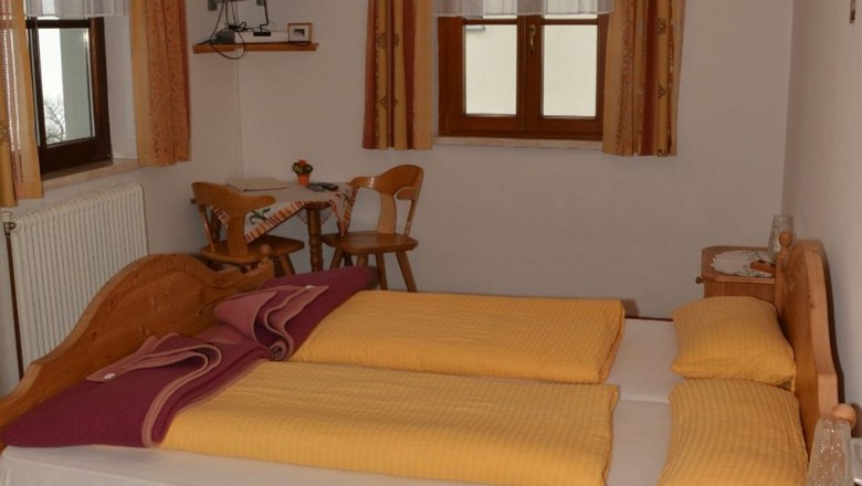 Cozy bedroom with double bed, wooden furniture and small table with chairs.