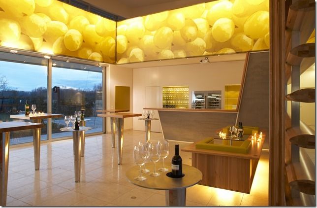 Modernes Verkostungszimmer in einem Weingut mit gelber Deckenbeleuchtung und Glaswänden.