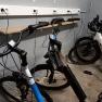 Drei E-Bikes in einer Garage, die an einer Steckdosenleiste aufgeladen werden.