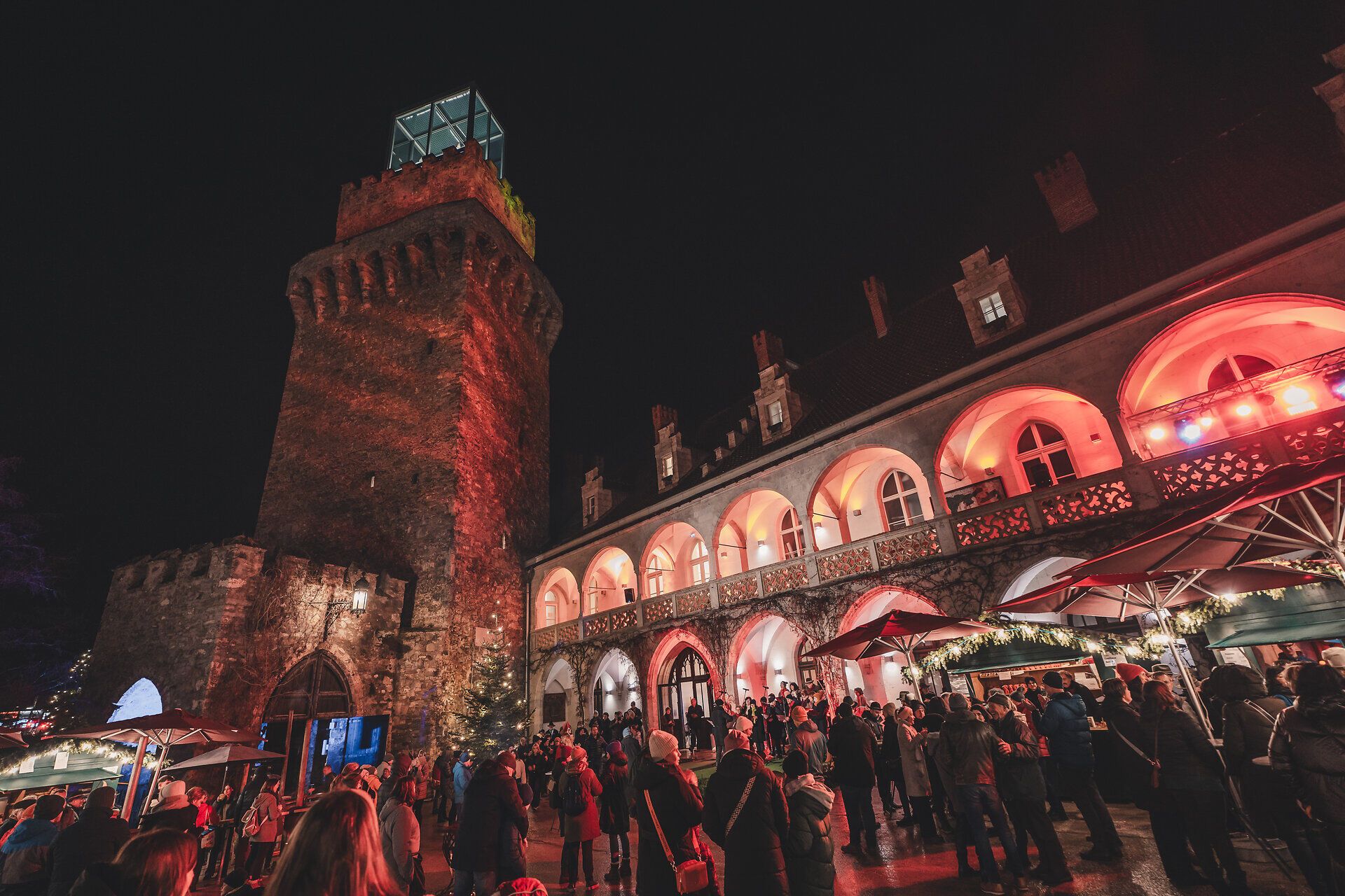 Abendliche Stimmung mit beleuchteter Kulisse auf dem Adventmarkt.